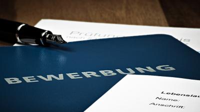 blaue Bewerbungsmappe darauf liegt der Lebenslauf und ein Stift