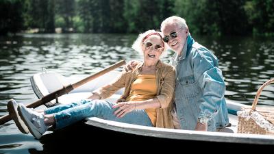 Fröhliches Rentnerpaar mit Sonnenbrille im Ruderboot