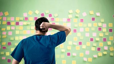 Mann steht vor Wand voller Post Its