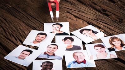 Bewerbungsfotos liegen auf einem Tisch und werden von Magnet angezogen