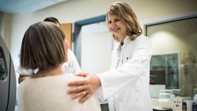 Ärztin spricht mit Patientin und berührt sie an der Schulter