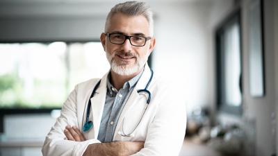 Ältere Ärzt mit verschränkten Armen 