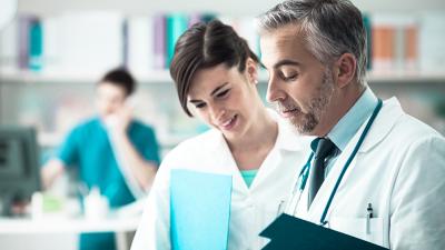 Arzt und Ärztin schaunen zusammen auf einen Bericht