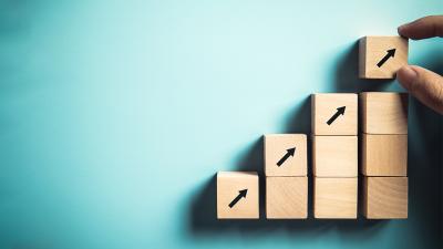 Holzblöcke, die immer weiter ansteigen, auf den obersten ein Pfeil aufsteigend