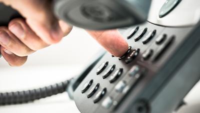 Telefon mit Hand, die eine Nummer wählt