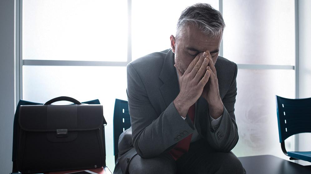 Nervöser Bewerber vor dem Vorstellungsgespräch mit Aktentasche und Anzug