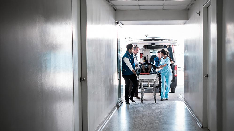 Patient wird von Ärzte-Team auf Trage vom Krankenwagen in die Notaufnahme gefahren